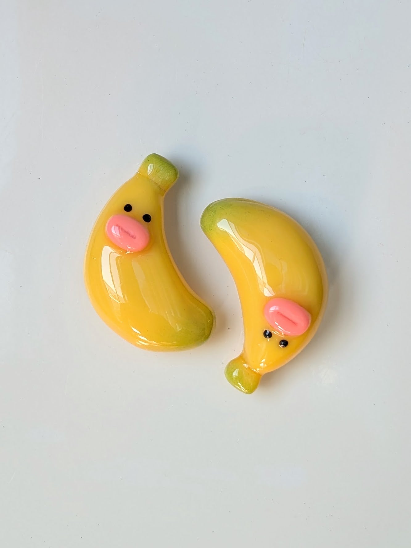 Two cartoon-style banana magnets on a light gray background