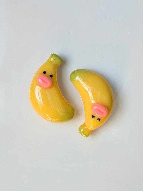 Two cartoon-style banana magnets on a light gray background
