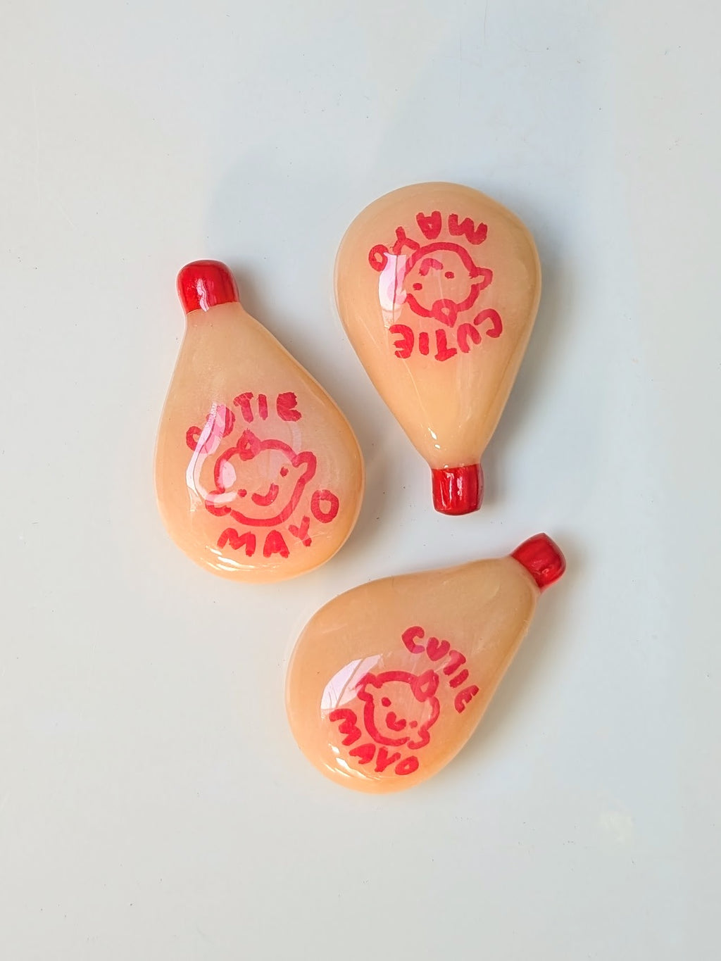 Three small peach-colored items with red accents and cartoon character prints on a light gray background.