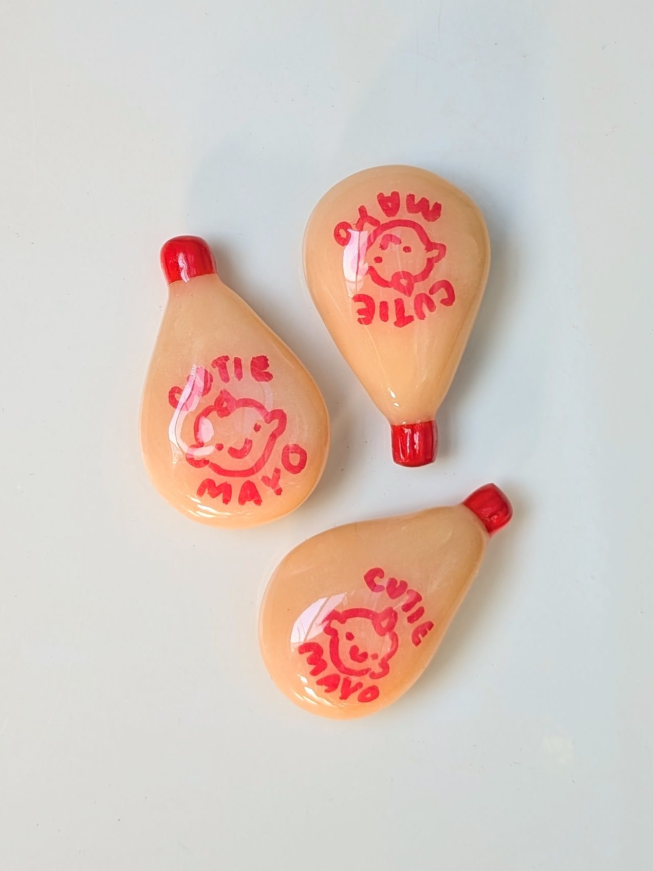 Three small peach-colored items with red accents and cartoon character prints on a light gray background.