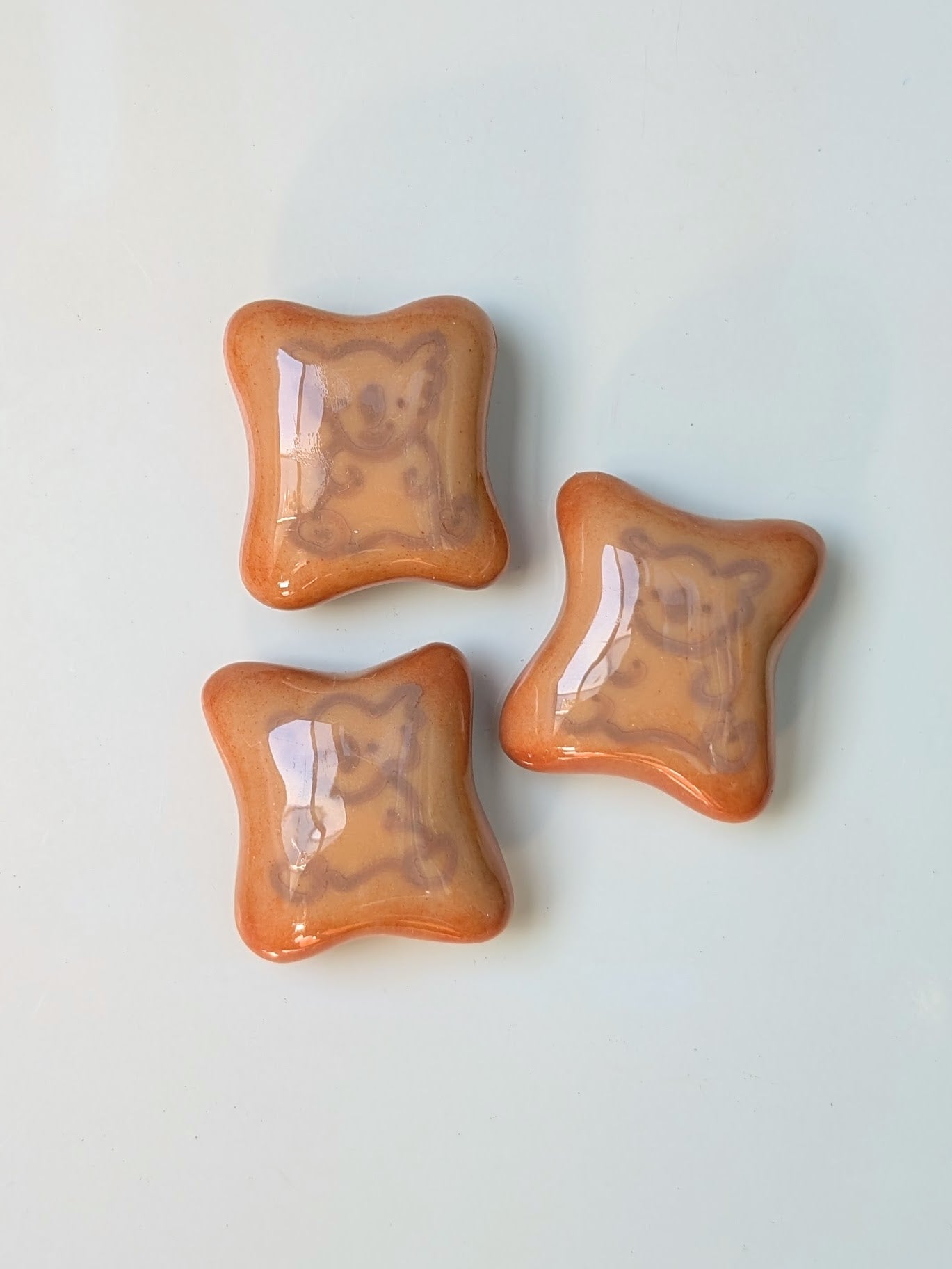 Three star-shaped orange objects on a light gray background