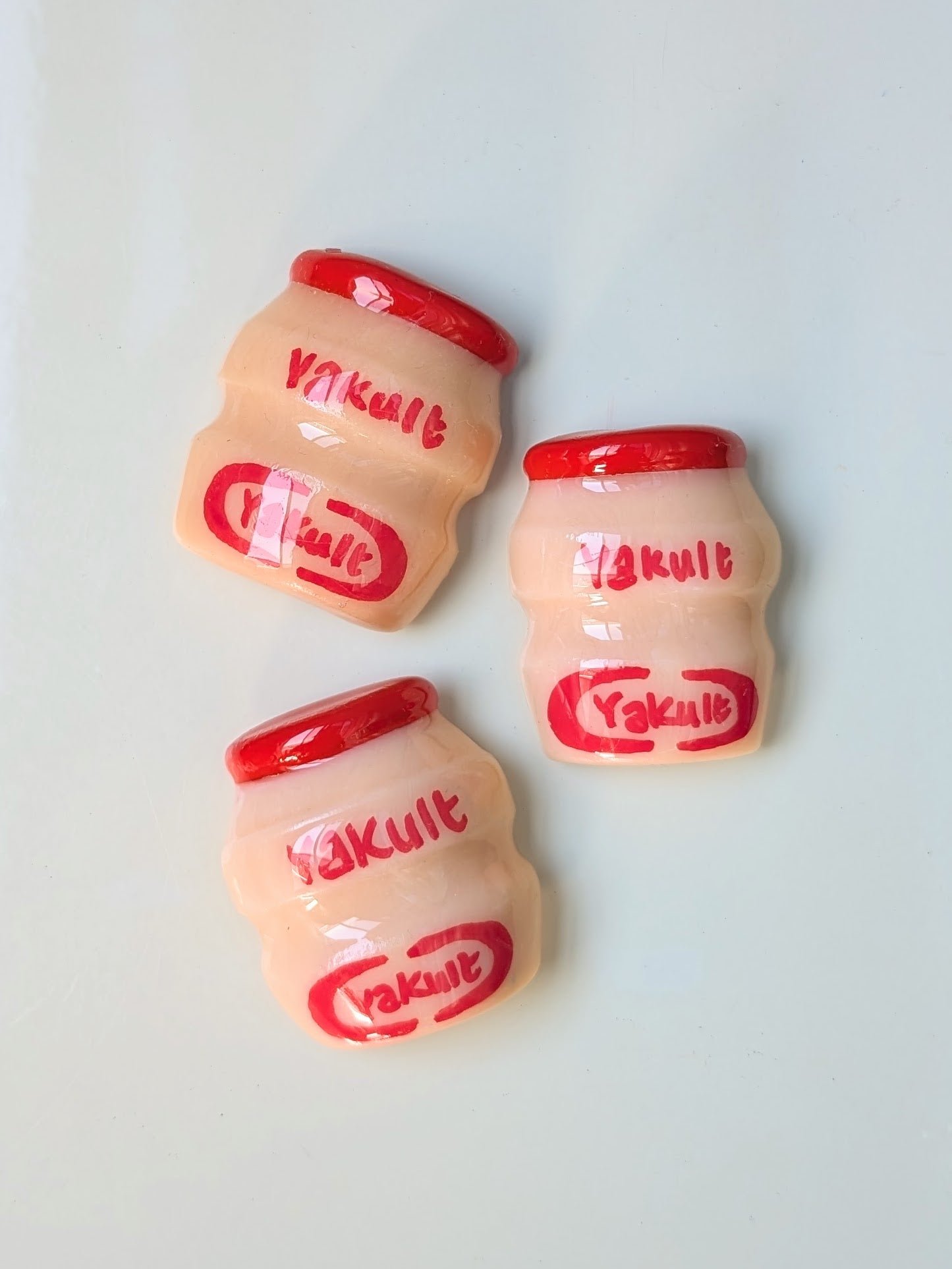 Three Yakult bottles with red lids on a white background